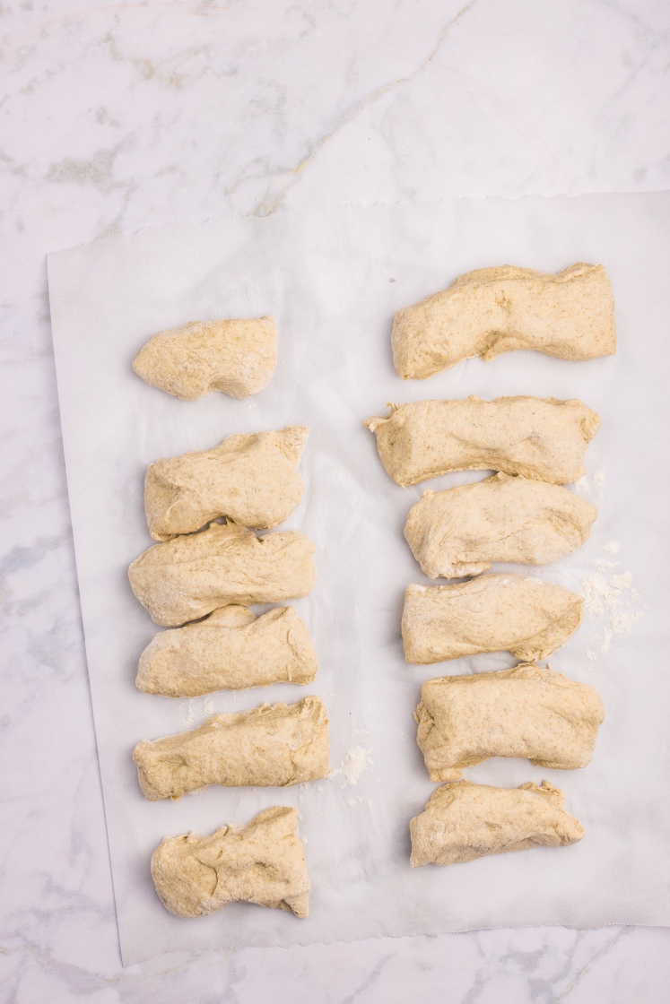 Portioned pieces of rye dough arranged on parchment paper, ready to be shaped into rolls.