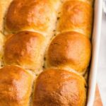 A close-up of golden-brown dinner rolls baked in a white rectangular dish.