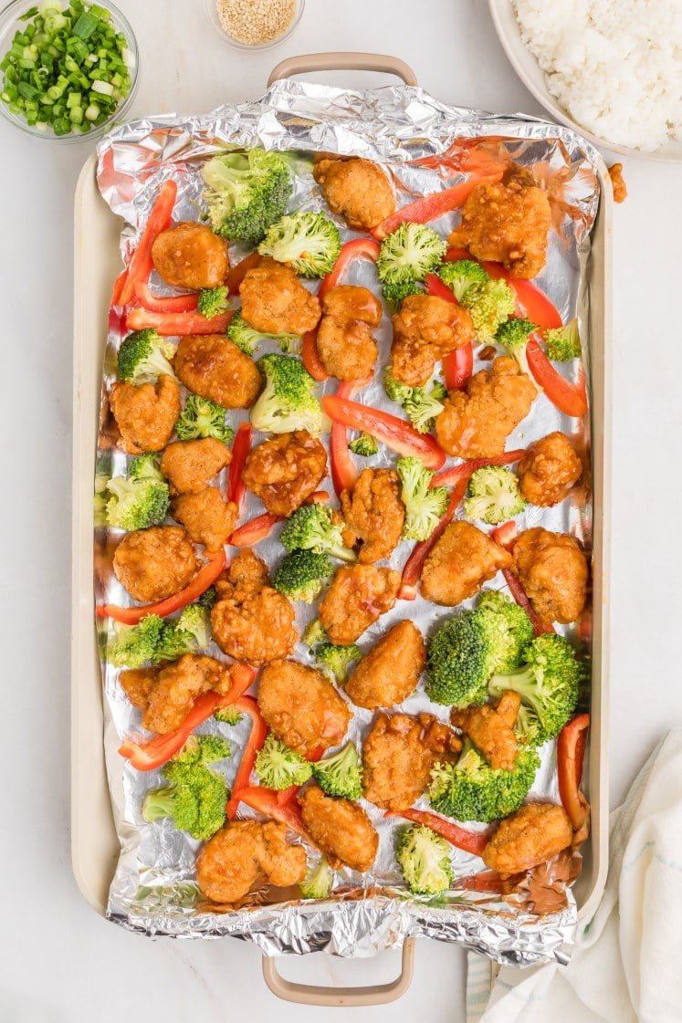 General Tso’s chicken with broccoli and red bell peppers on a sheet pan.
