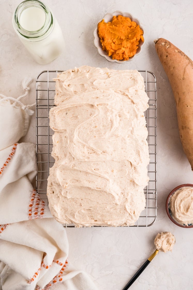 Sweet potato loaf topped with whipped frosting on a cooling rack.