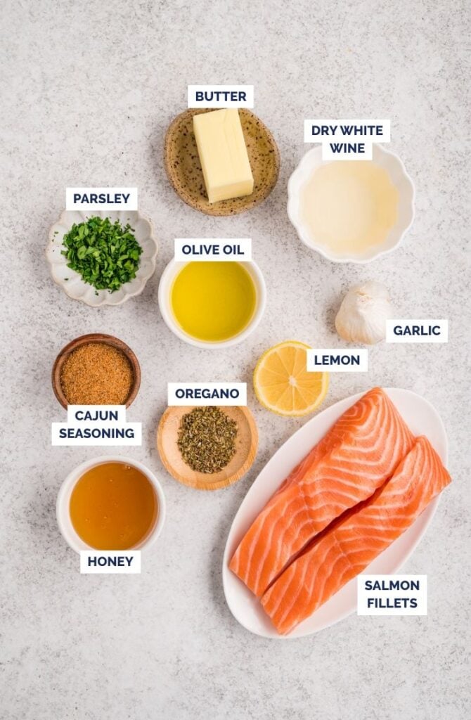 Ingredients for Cajun salmon laid out, including salmon fillets, butter, lemon, garlic, herbs, and seasonings.