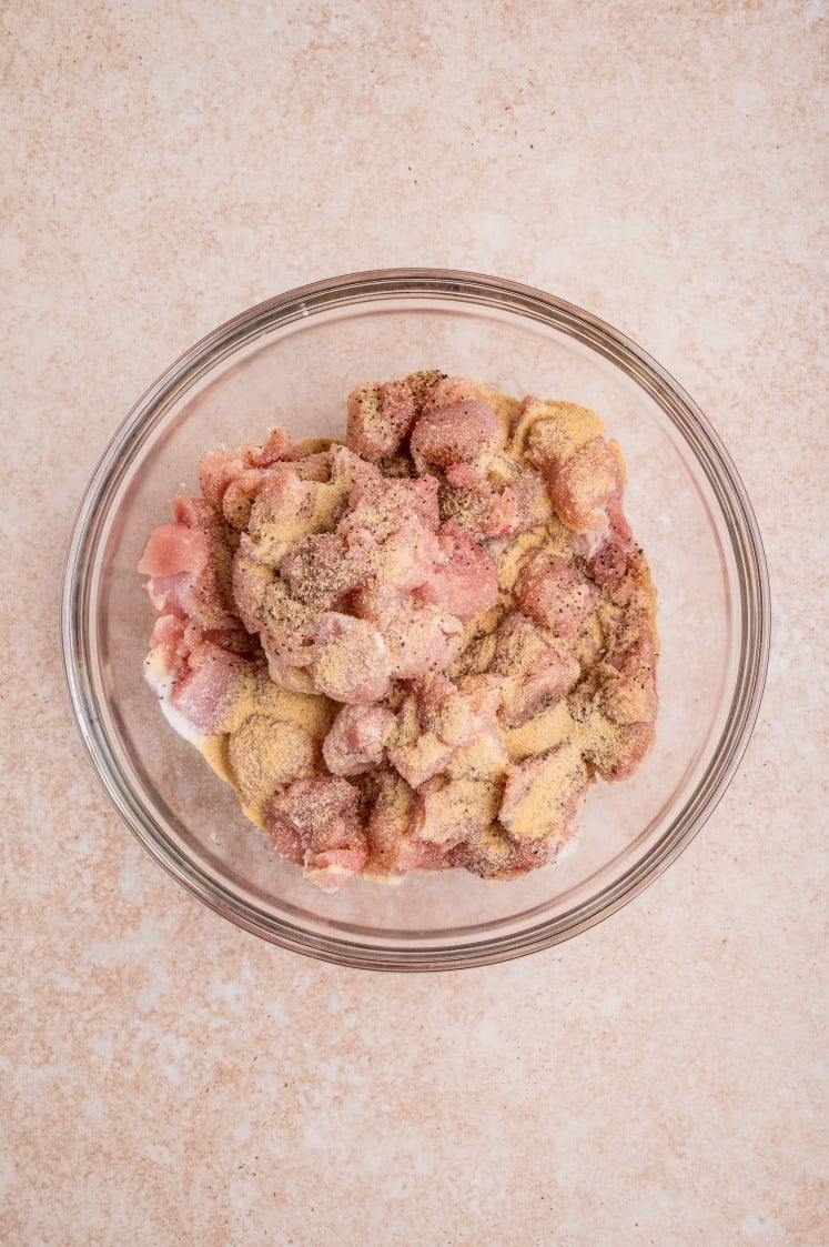 Seasoned raw chicken pieces in a glass bowl.