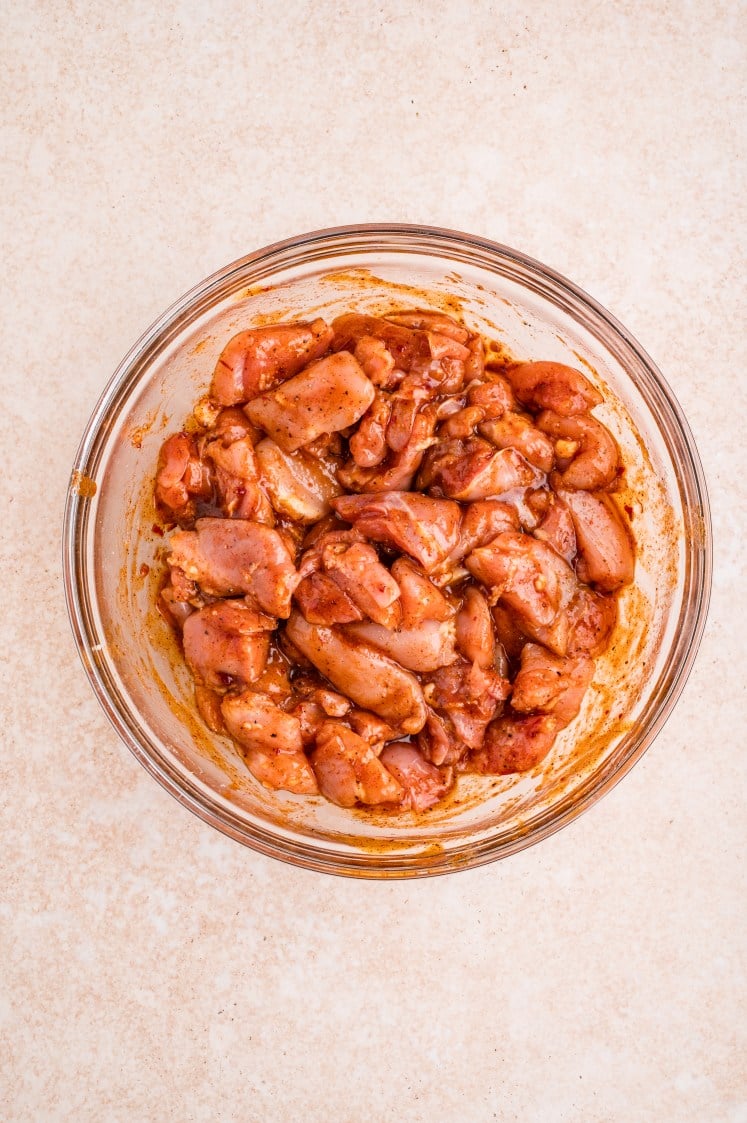 Marinated chicken pieces coated in chipotle sauce in a glass bowl.