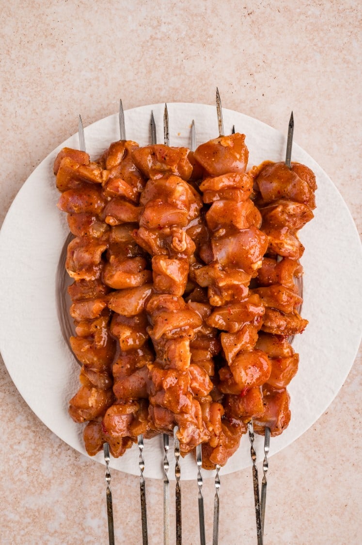 Raw chipotle-marinated chicken threaded onto skewers.