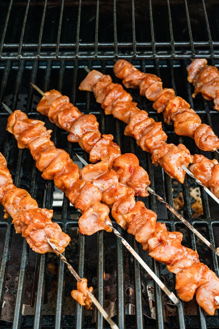 Chipotle chicken skewers cooking on a grill.