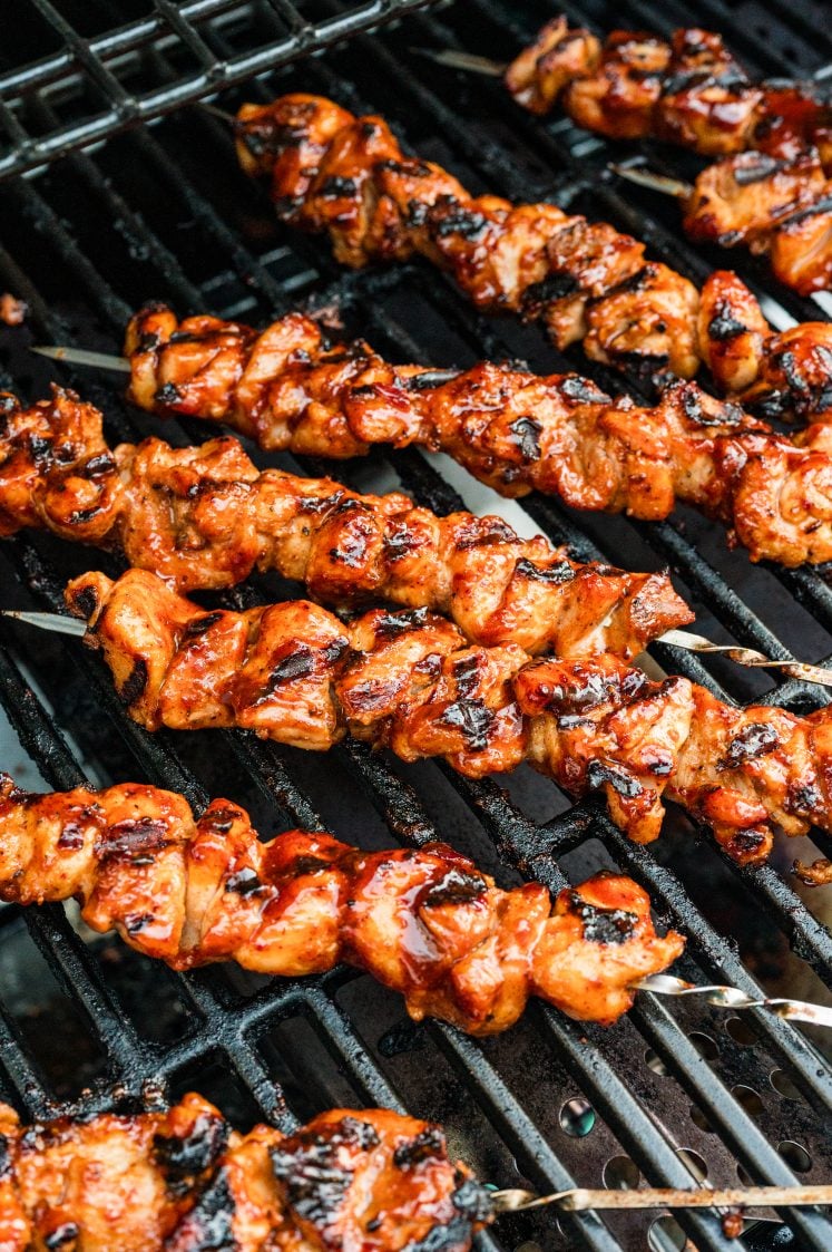 Grilled chipotle chicken skewers with charred edges on a grill.