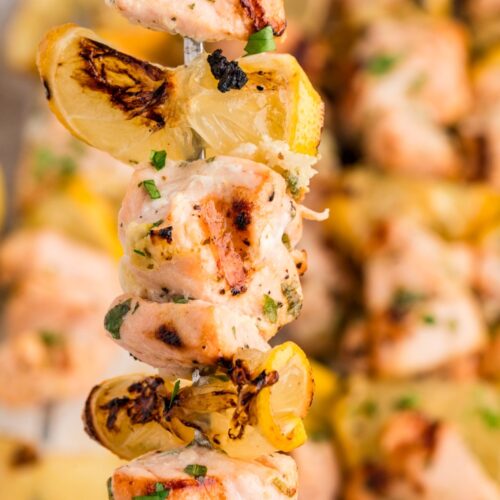 Grilled salmon skewers with lemon slices charred until lightly caramelized, finished with fresh herbs for a bright, savory bite.