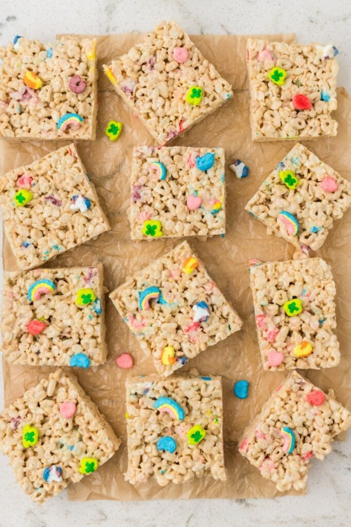 Lucky Charms rice krispies treats cut into squares on parchment paper.