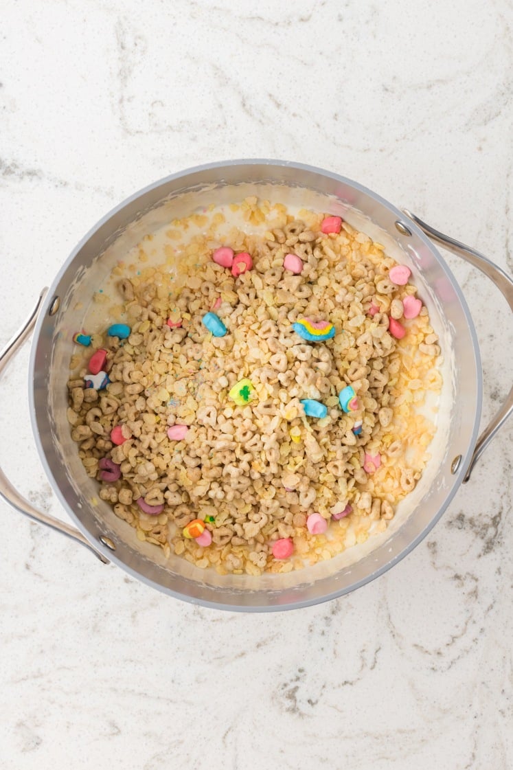 Cereal mixed into melted marshmallow in a saucepan.
