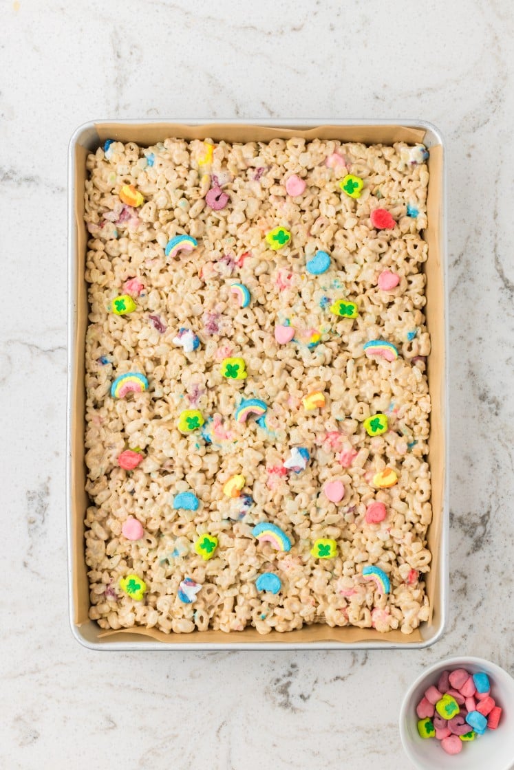 Lucky Charms Rice Krispies mixture pressed into a lined baking pan.