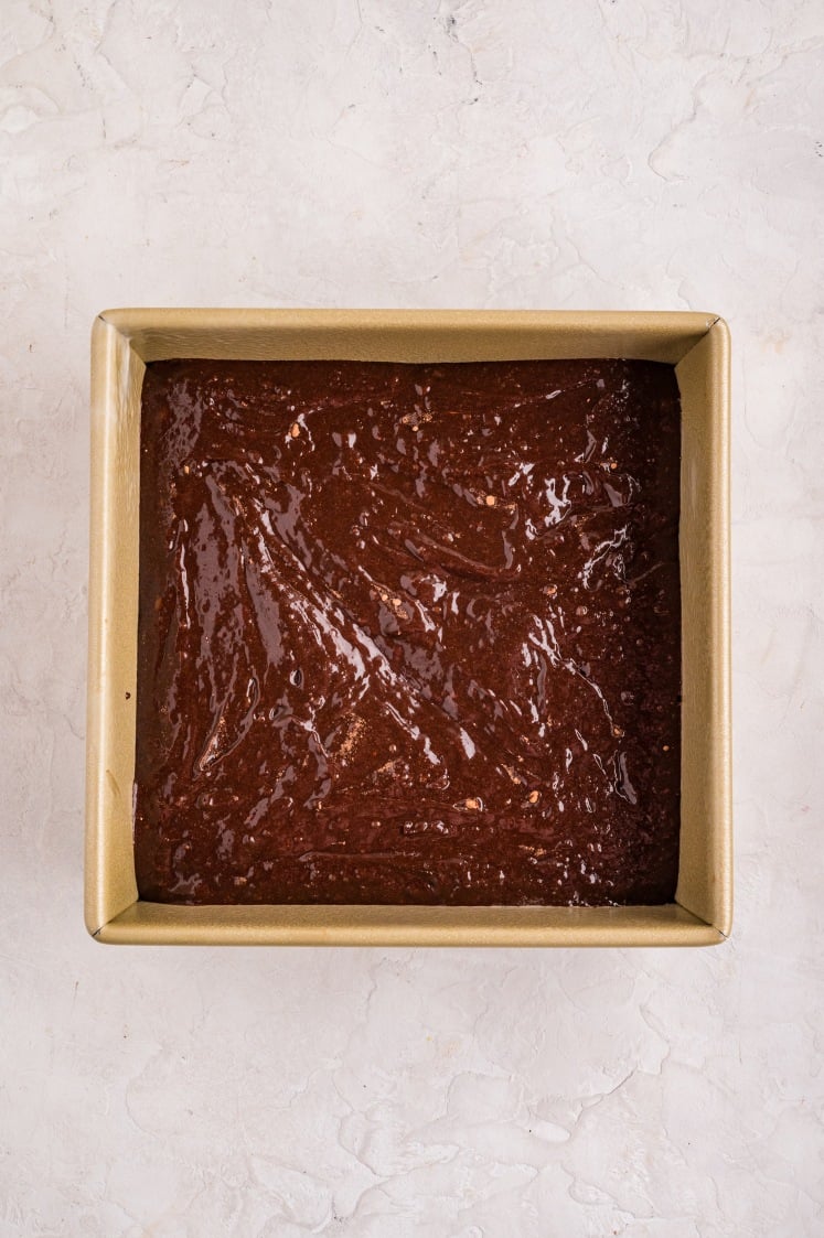 Brownie batter spread evenly into the prepared pan, smoothed out and ready to bake.