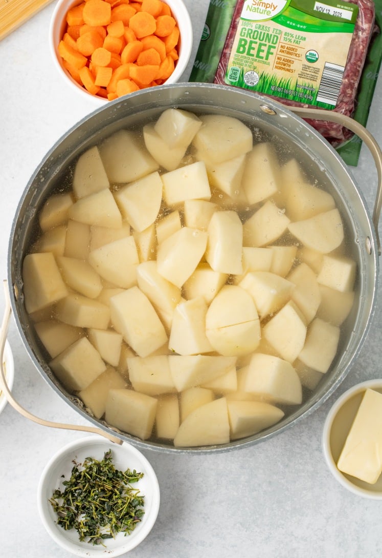 Peeled russet potatoes simmering in a pot of water, prepped and ready to be mashed for the shepherd’s pie topping.