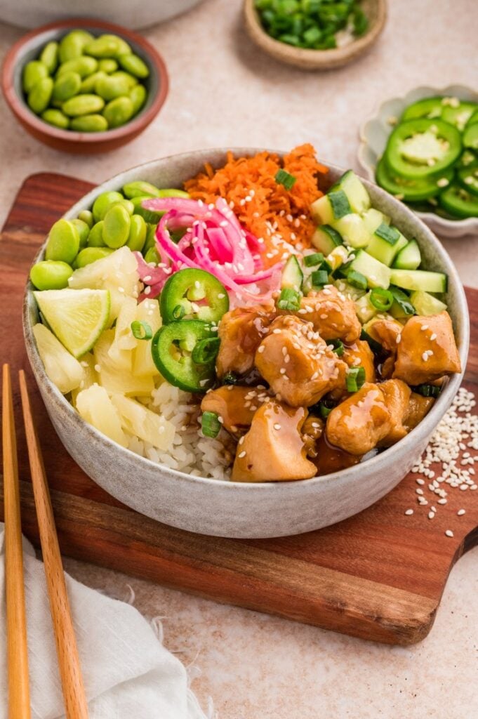 Chicken poke bowl with rice, glazed chicken, edamame, cucumber, pickled red onions, pineapple, and jalapeño.