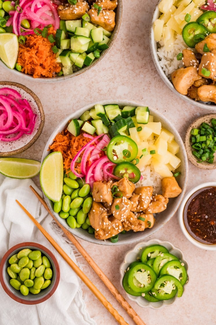 Chicken poke bowls with rice, edamame, cucumber, pineapple, pickled onions, and jalapeños.