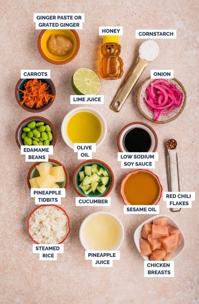Chicken poke bowl ingredients with labeled sauces, vegetables, rice, pineapple, and raw chicken.