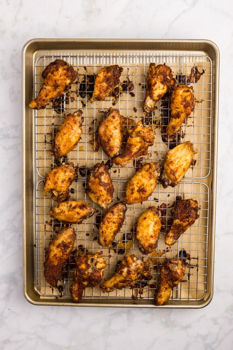 Crispy baked spice-rubbed chicken wings on a wire rack over a sheet pan.