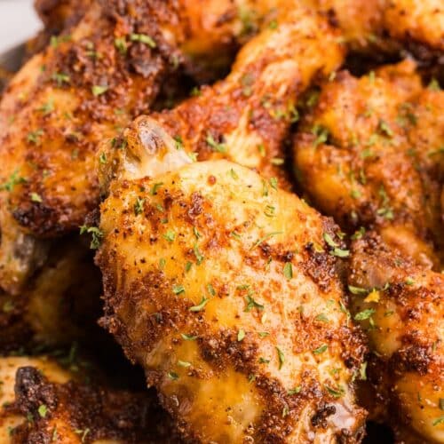 Close-up of crispy spice rubbed chicken wings with golden, seasoned skin.