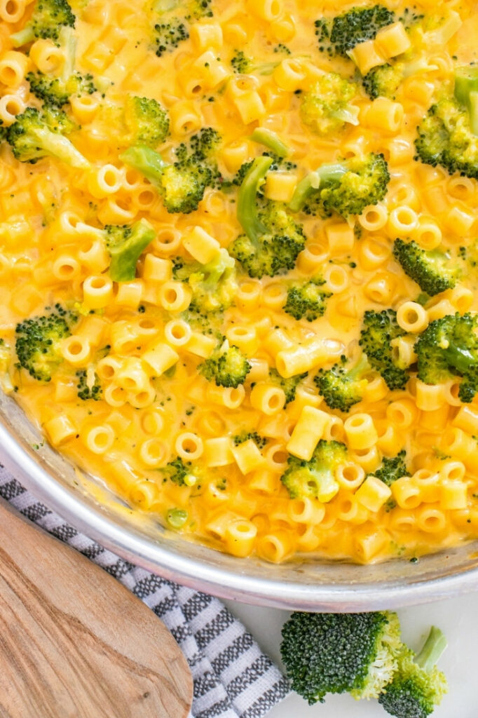 Close-up of a skillet filled with broccoli cheddar ditalini pasta in a creamy orange cheese sauce.