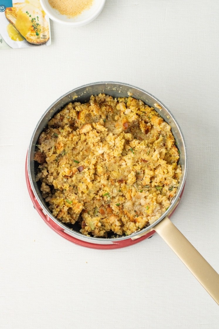 A saucepan of fully mixed and moistened herb stuffing, golden and crumbly.