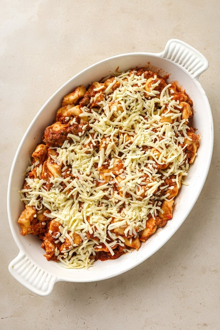 Top-down shot of the casserole fully covered with shredded mozzarella and ready for the oven.