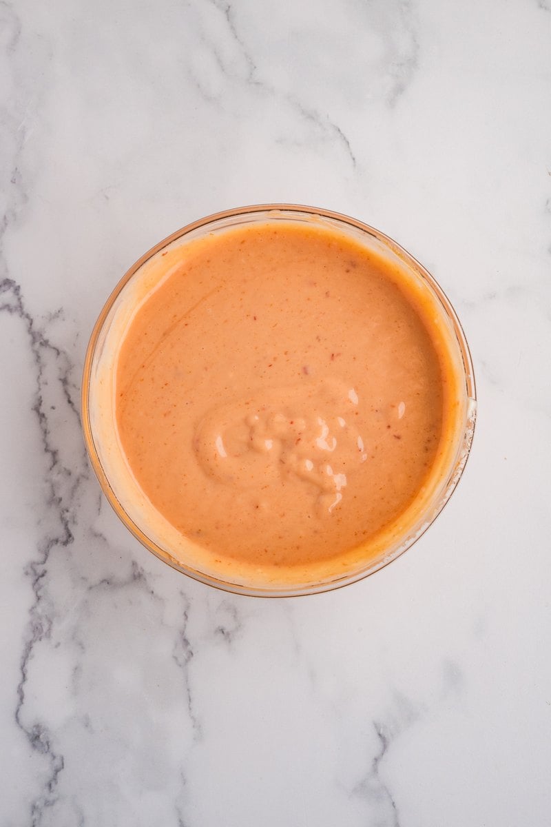 Whisked creamy orange boom boom sauce in a glass bowl.