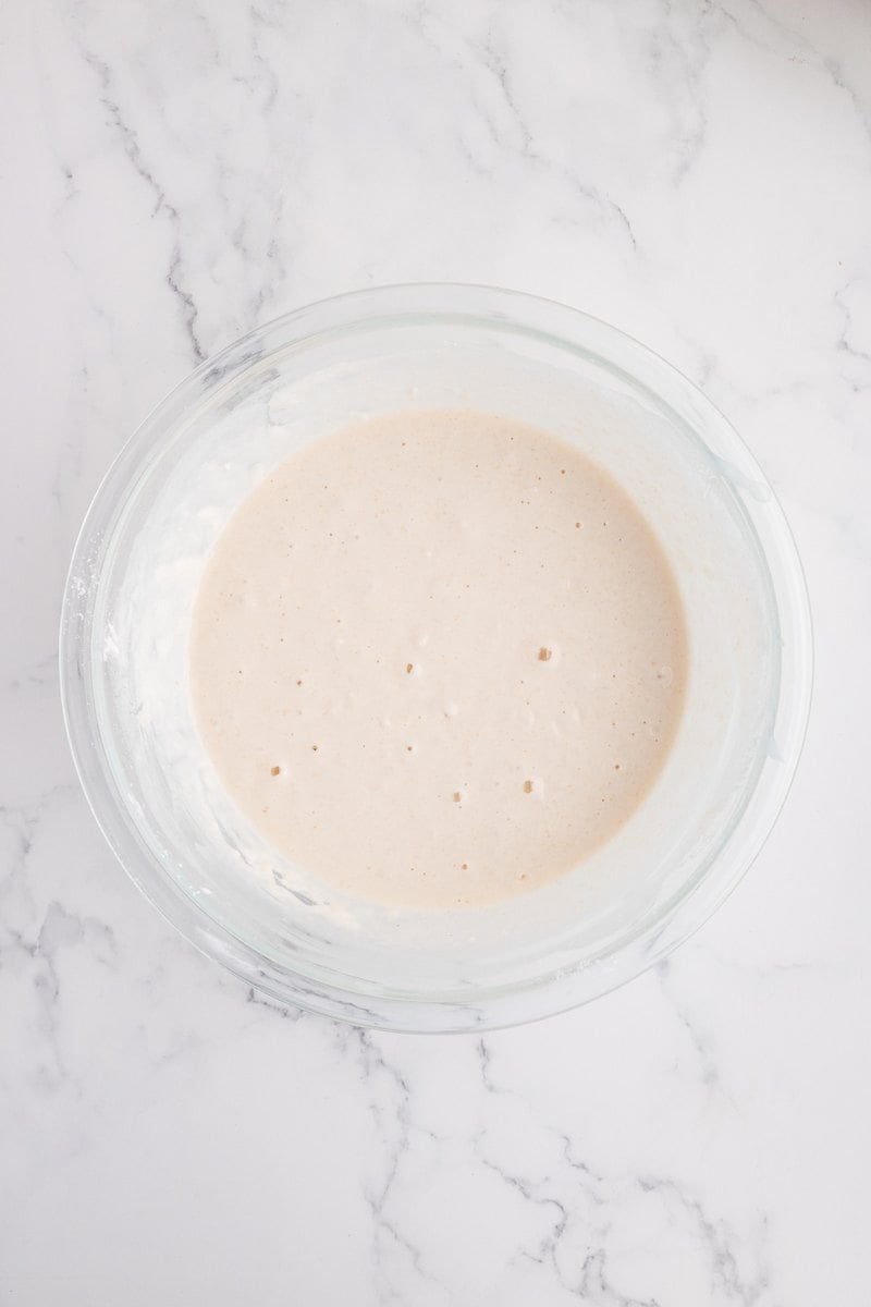 Thick, bubbly soda-water batter whisked smooth in a glass bowl.