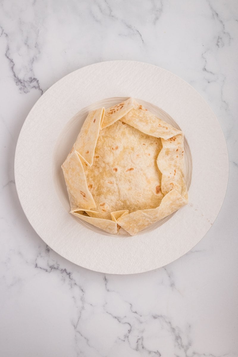 The large tortilla folded up and over the small tortilla into a sealed hexagon shape.