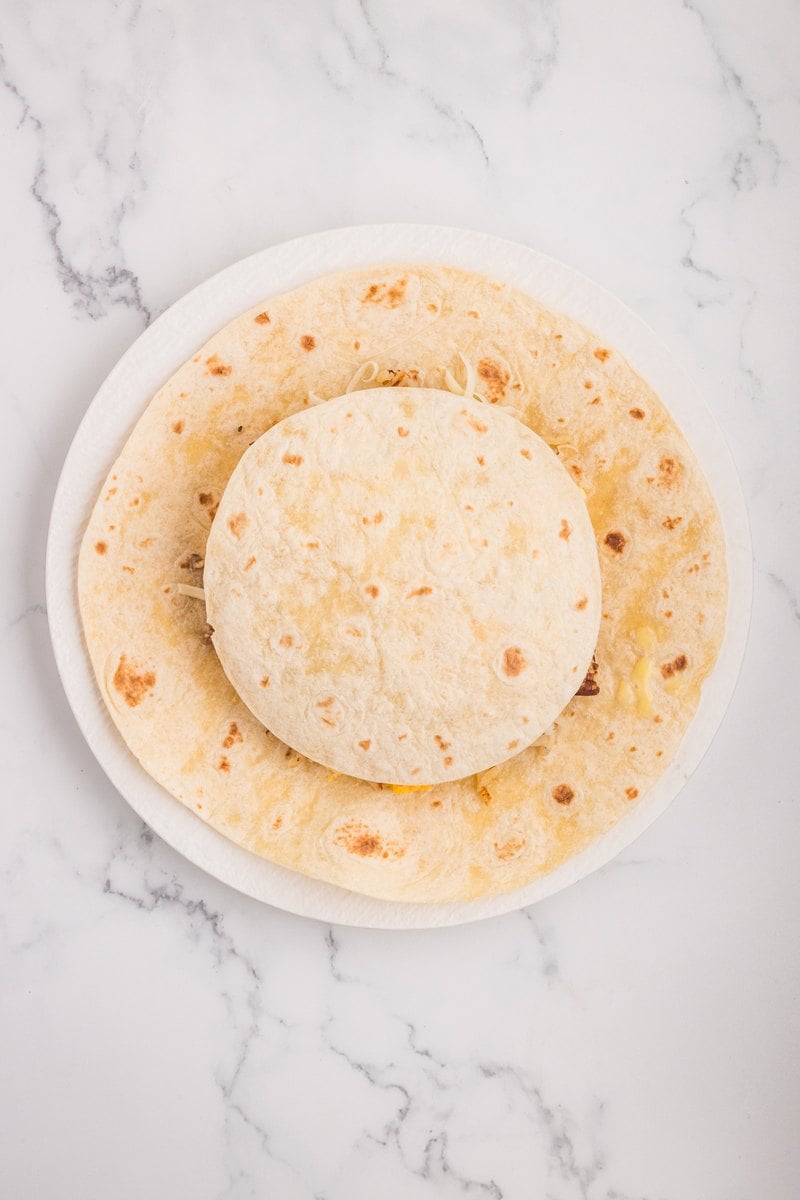 A small tortilla placed on top of the filling in the center of the large tortilla.