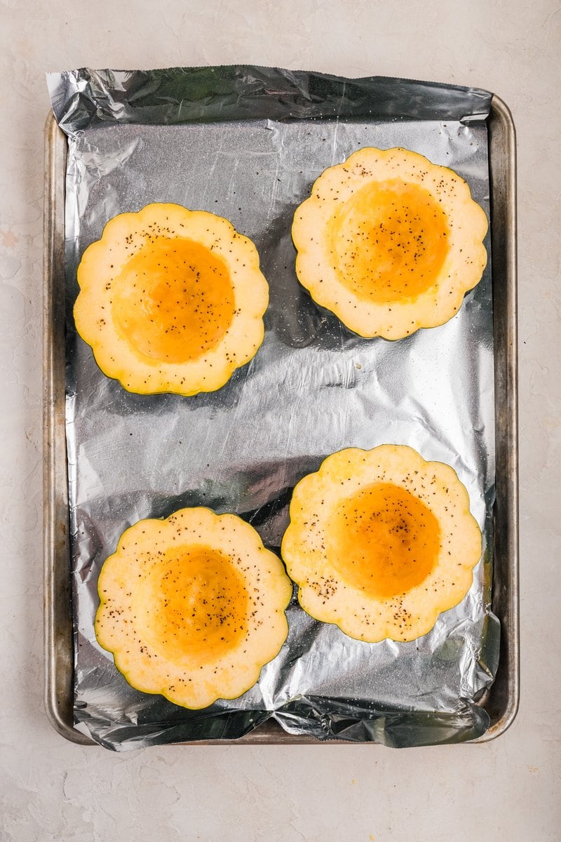 Hollowed acorn squash halves brushed with olive oil and sprinkled with salt and pepper.