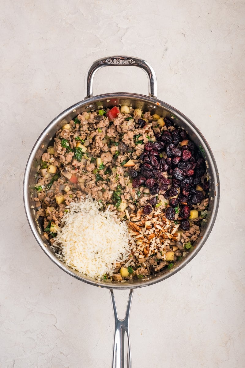 Dried cranberries, chopped pecans, and Parmesan added on top of the cooked sausage filling in the skillet.